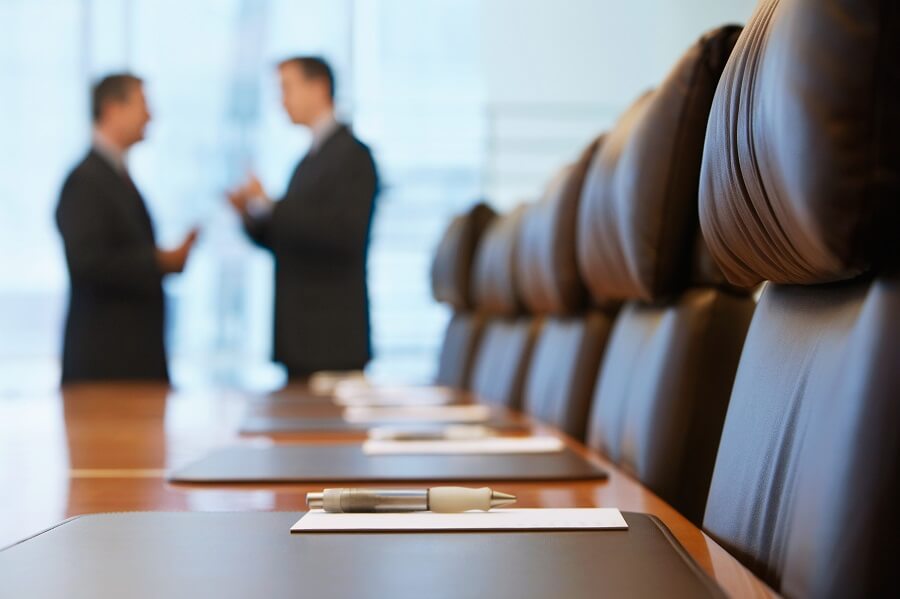 Two individuals discuss remote audio-visual management at the end of a sophisticated meeting table.